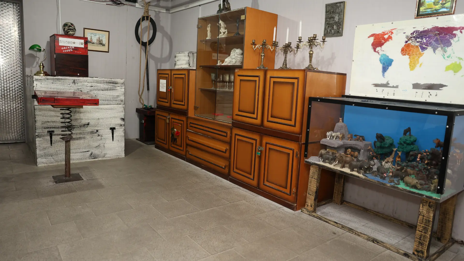 Unutrašnjost Poaro escape sobe sa drvenim ormarima, staklenom vitrinom, mapom sveta, svećnjacima i rekvizitima za rešavanje misterije.