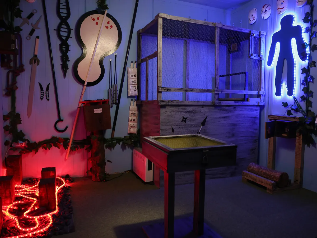 Naruto escape room sa drvenim kavezom, nindža rekvizitima i plavo osvetljenom siluetom na zidu