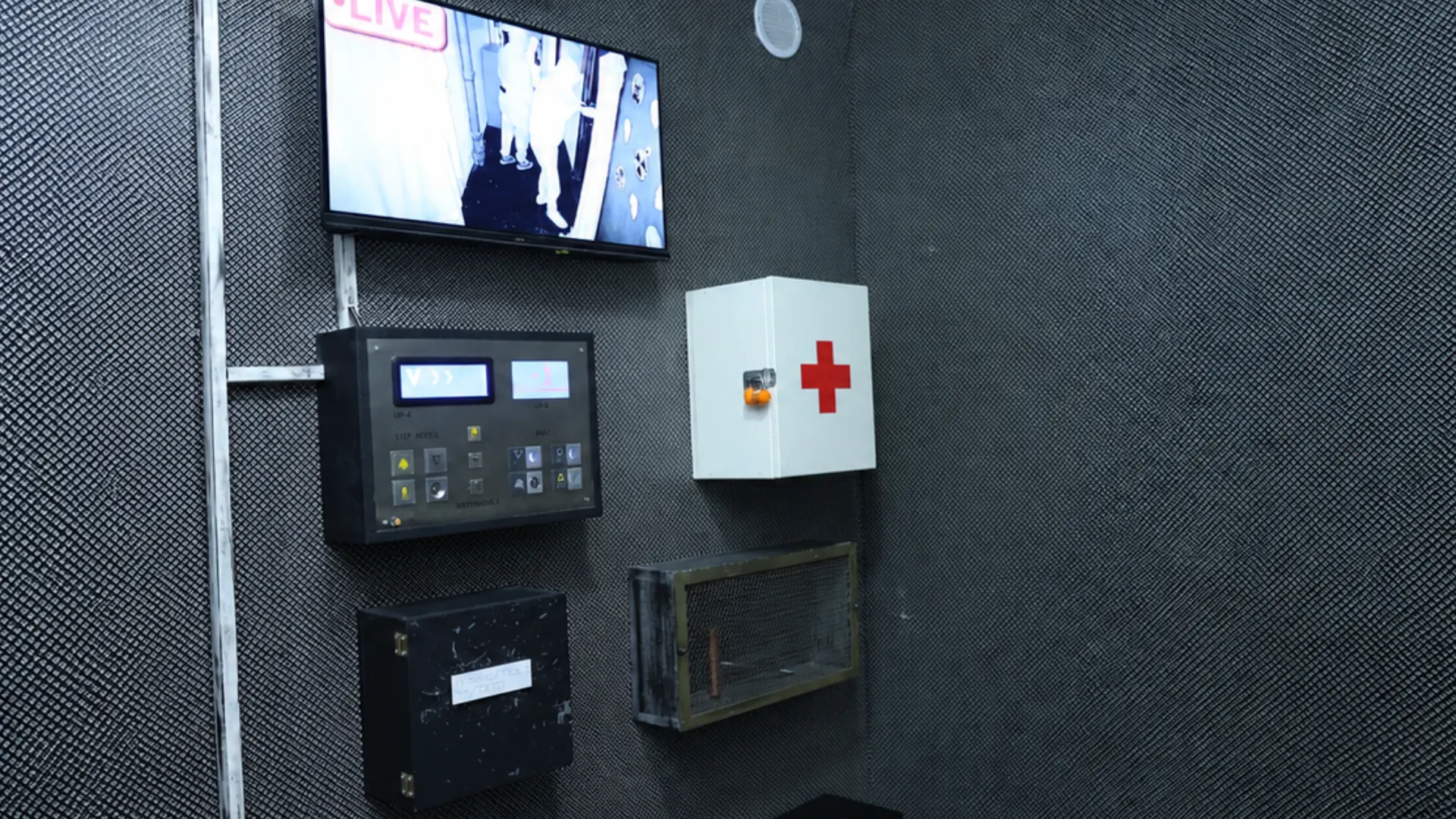 Unutrašnjost Panic Room escape sobe sa ekranom za video-nadzor, kontrolnom tablom, ormarićem za prvu pomoć i metalnim kutijama na zidu.