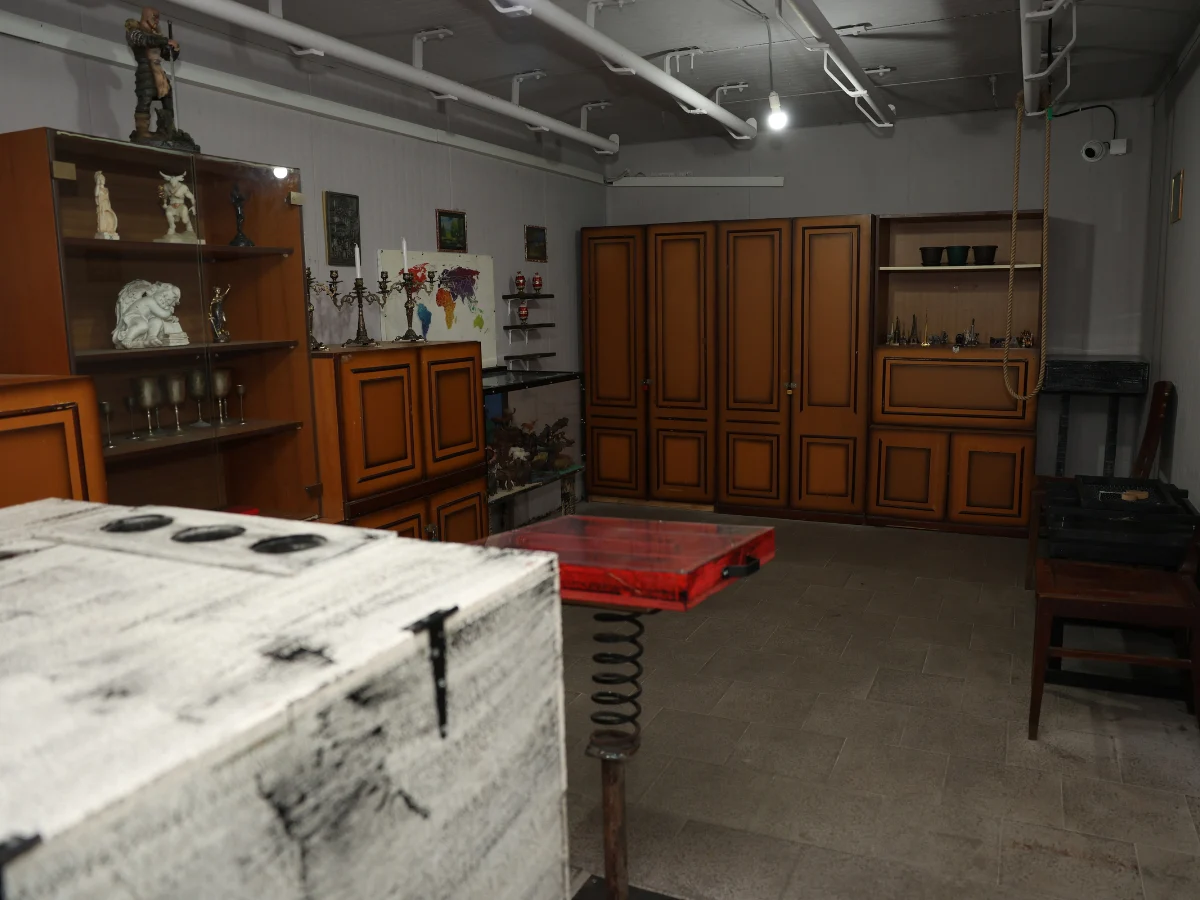 Poaro escape room sa drvenim ormarima, vitrinom sa figuricama i belim sandukom u prvom planu